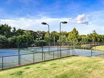 A tennis court surrounded by a fence and trees at Quail Ridge Apartment Homes, Bartlett, 38135